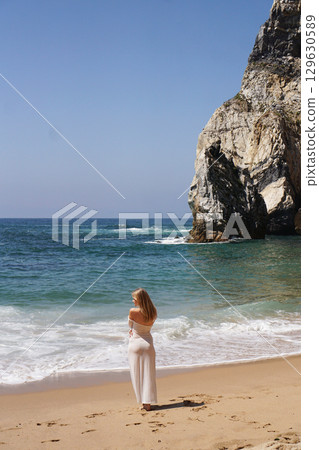In Solitude by the Ocean A Woman Walking Alone Peacefully on the Beautiful Scenic Beachside 129630589