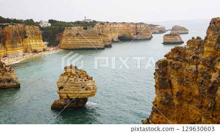 The coastal cliffs and stunning golden beach views create an unforgettable experience 129630603