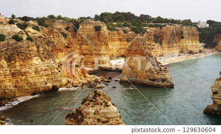 The coastal cliffs and stunning golden beach views create an unforgettable experience 129630604