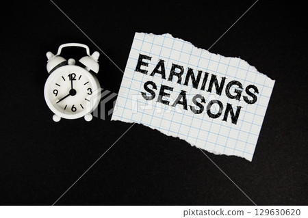 Earnings Season text written on paper with alarm clock on black background 129630620