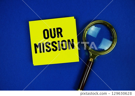 Our Mission text on sticky note with magnifying glass on blue background 129630628