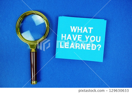 What Have you Learned? text on sticky note with magnifying glass on navy blue background 129630633