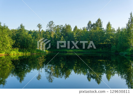 Beautiful summer landscape with forest lake and reflection of trees in water Beautiful summer landscape with forest lake and reflection of trees in water 129630811