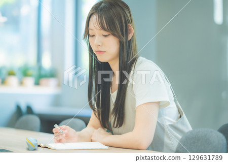 一名女大學生一邊看著筆記本一邊思考 129631789