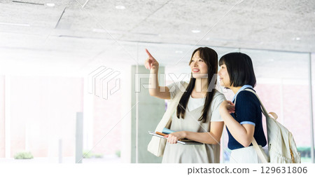 Two female college students pointing and talking on campus 129631806