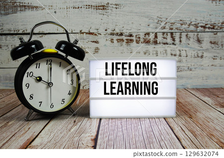 Lifelong Learning text on light box with alarm clock on wooden background Lifelong Learning text on light box with alarm clock on wooden background 129632074