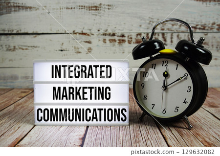 Integrated Marketing Communications text on light box with alarm clock on wooden background 129632082