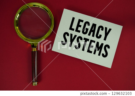 Legacy Systems text written on paper with magnifying glass 129632103