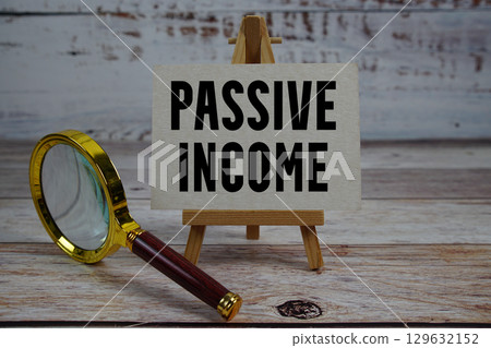Passive Income text written on paper with magnifying glass 129632152