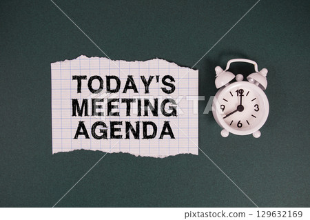 Today's Meeting Agenda text written on paper with alarm clock on green background 129632169