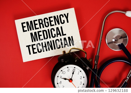 Emergency Medical Technician text written on paper card with stethoscope and alarm clock on red background 129632188