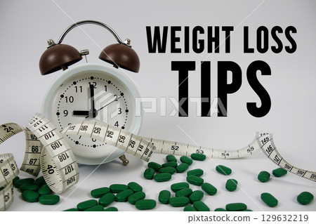 Weight Loss Tips text with medicine, alarm clock and measuring tape on white background Weight Loss Tips text with medicine, alarm clock and measuring tape on white background 129632219