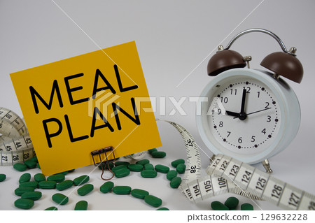 Meal Plan text with medicine, alarm clock and measuring tape on white background Meal Plan text with medicine, alarm clock and measuring tape on white background 129632228