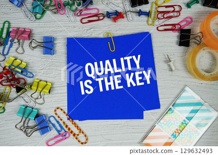 Quality is the Key text on stick note with stationery on concrete background 129632493