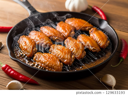 Sizzling Buffalo Wings in a Cast Iron Skillet with Garlic and Peppers 129633193