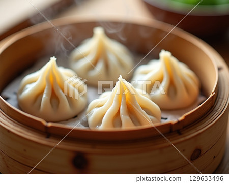 Steaming Close-Up Traditional Pork Xiao Long Bao Dumpling in Bamboo Steamer 129633496