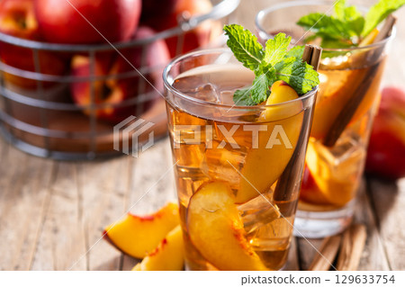 Refreshing peach iced tea in glass with ice cubes 129633754