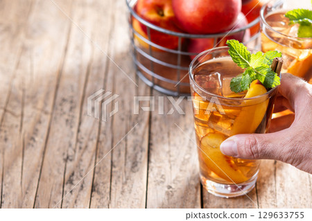 Refreshing peach iced tea in glass with ice cubes 129633755