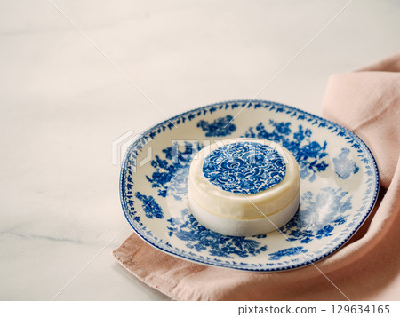 Pastry dessert in Gzhel rustic style. Sweet pastry decorated blue flowers photo printing on sugar paper. Mini cake Gzhel on plate over white marble tabletop background. Copy space. Pastry dessert in Gzhel rustic style. Sweet pastry decorated blue flowers photo printing on sugar paper. Mini cake Gzhel on plate over white marble tabletop background. Copy space. 129634165