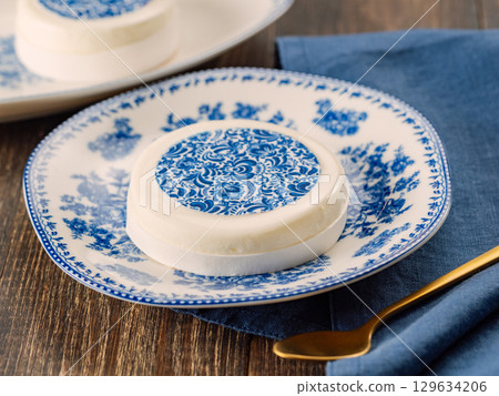 Pastry dessert in Gzhel rustic style. Sweet pastry decorated blue flowers photo printing on sugar paper. Mini cake Gzhel on plate over wooden tabletop background. Closeup Pastry dessert in Gzhel rustic style. Sweet pastry decorated blue flowers photo printing on sugar paper. Mini cake Gzhel on plate over wooden tabletop background. Closeup 129634206