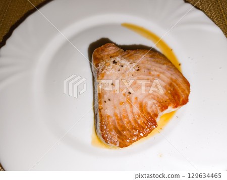 Grilled tuna steak with salt and pepper resting on white plate Grilled tuna steak with salt and pepper resting on white plate 129634465