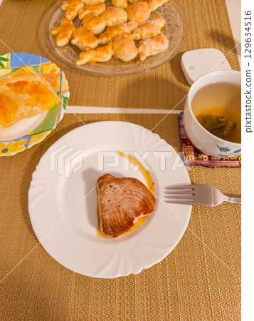 Grilled tuna steak served on white plate with dessert and tea Grilled tuna steak served on white plate with dessert and tea 129634516