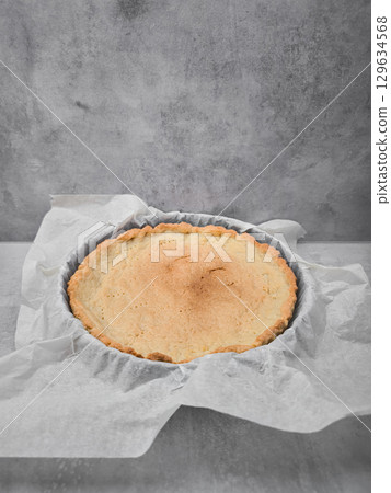 Empty pie crust cooling on baking paper in a kitchen 129634568