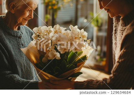 Florist giving white orchids bouquet to elderly woman for valentine's day 129634684