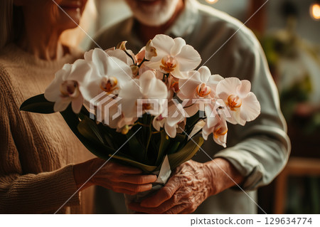 Senior couple holding a bouquet of orchids for valentine's day 129634774