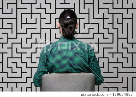 A woman is standing near a wall with a drawing of a labyrinth. Brainstorming, thinking 129634892