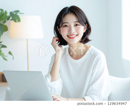 一位年輕女子帶著燦爛的笑容，面對著電腦 129634947