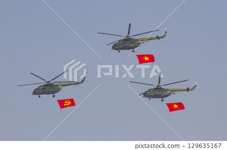 A Unit Mi-17 Helicopters Of Vietnam People's Air Force Flying With National Flag And Communist Party Flag At the 50th Anniversary Of The Reunification Day. 129635167