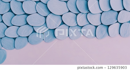 Decorative light blue pebbles arranged on a soft pastel background for creative projects 129635903