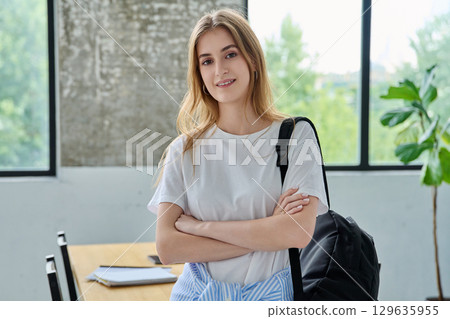 Portrait of student girl, positive smiling beautiful blonde with backpack looking at camera Portrait of student girl, positive smiling beautiful blonde with backpack looking at camera 129635955
