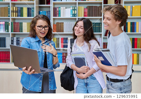 Two teenage students meeting talking with female teacher in library 129635991
