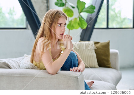 Sad unhappy upset young woman sitting at home on sofa, face close-up Sad unhappy upset young woman sitting at home on sofa, face close-up 129636005