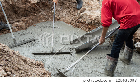 Workers are helping to level the concrete floor. 129636098
