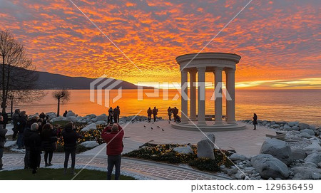 Tourists Witness a Fiery Sunrise at a Coastal Rotunda 129636459