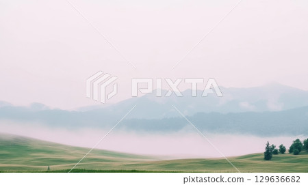 Misty morning landscape with rolling hills and distant mountains in serene nature 129636682