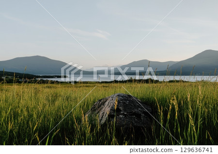 Scenic view of mountains and tranquil lake surrounded by green grass at sunset 129636741