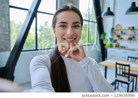 Close-up selfie portrait of teenage female looking at web camera 129636990