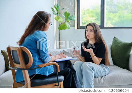 Sad teenage girl student talking with social psychologist, therapist, counselor 129636994
