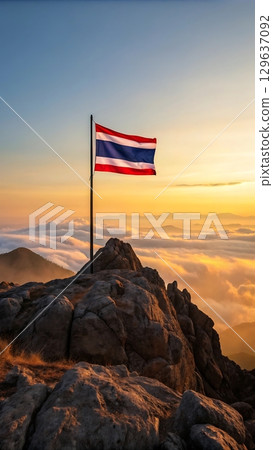 Thailand flag waving atop rocky mountain peak against a cloudy sunset Thailand flag waving atop rocky mountain peak against a cloudy sunset 129637092