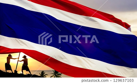 Two men holding a large thailand flag on a tropical beach at sunset time 129637103