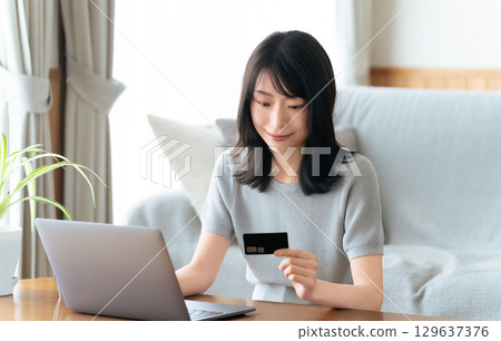 A woman shopping on a computer using a credit card 129637376