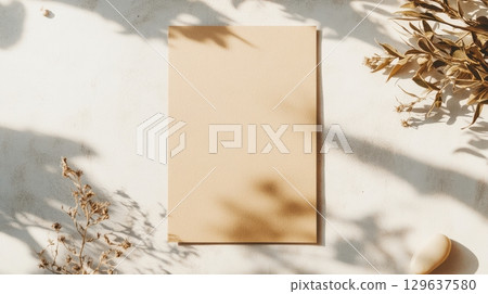 Blank kraft card mockup with soft plant shadows on a textured concrete wall, styled in organic tones and minimal light 129637580