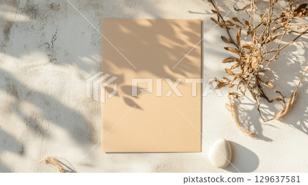 Blank kraft paper card mockup styled with soft botanical shadows and natural elements on textured concrete wall in minimal neutral tones with backlit morning light 129637581