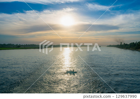Sunset Over the Nile River Near Luxor With a small Boat. Sunset Over the Nile River Near Luxor With a small Boat. 129637990