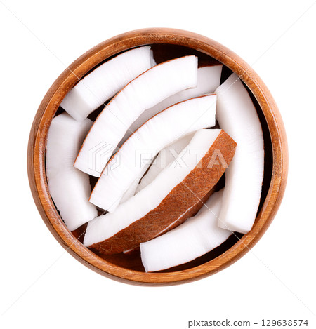 Raw coconut meat, in a wooden bowl. Opaque white flesh of a fresh and young coconut, cut into strips, and ready to eat. Seed of the palm tree Cocos nucifera. Isolated on white background, food photo. Raw coconut meat, in a wooden bowl. Opaque white flesh of a fresh and young coconut, cut into strips, and ready to eat. Seed of the palm tree Cocos nucifera. Isolated on white background, food photo. 129638574