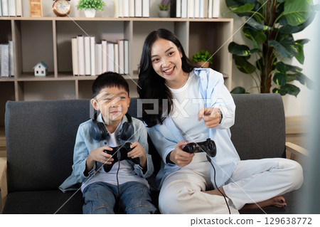 Gaming Together. Mother and son enjoying video games on the couch. Gaming Together. Mother and son enjoying video games on the couch. 129638772